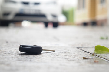 Lost car key lies on the pavement near a vehicle