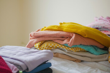 Neatly folded clothes stacked on a bed in a cozy room