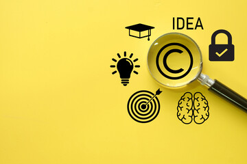 Magnifying glass on a copyright symbol, surrounded by icons for idea, knowledge,goal on yellow...
