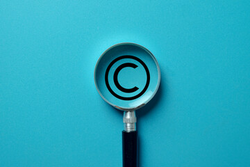 Concept of a copyright audit. A magnifier examines the copyright logo on blue background...