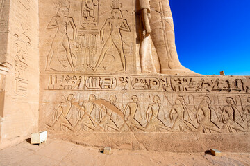 Detailed close up of ancient Egyptian carvings and hieroglyphs on the exterior wall of the Abu Simbel Temple in Aswan, Egypt, showcasing historical artwork.