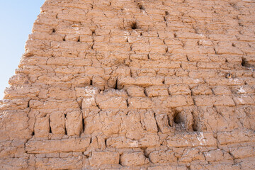 Close-up of an ancient mud brick wall at Abu Simbel, Aswan, Egypt, showing weathering and small holes, likely sparrow nests. This texture offers a glimpse into historical construction.