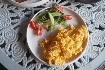 Delicious scrambled eggs with fresh salad and tomatoes