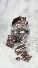 Crispy brownies arranged on a glass jar and white ceramic plate with a white marble background. isolate objects and background