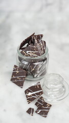 Crispy brownies arranged on a glass jar and white ceramic plate with a white marble background....