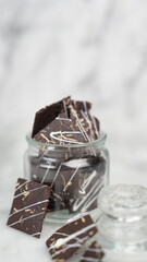 Crispy brownies arranged on a glass jar and white ceramic plate with a white marble background....