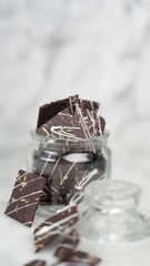 Crispy brownies arranged on a glass jar and white ceramic plate with a white marble background....
