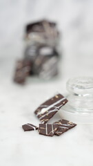 Crispy brownies arranged on a glass jar and white ceramic plate with a white marble background....