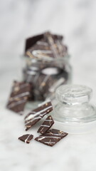 Crispy brownies arranged on a glass jar and white ceramic plate with a white marble background....