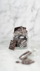 Crispy brownies arranged on a glass jar and white ceramic plate with a white marble background....