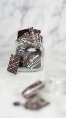 Crispy brownies arranged on a glass jar and white ceramic plate with a white marble background. isolate objects and background