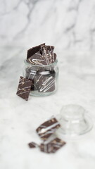 Crispy brownies arranged on a glass jar and white ceramic plate with a white marble background....