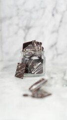 Crispy brownies arranged on a glass jar and white ceramic plate with a white marble background....
