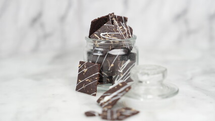 Crispy brownies arranged on a glass jar and white ceramic plate with a white marble background....