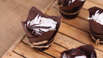 catherine chocolate cake wrapped in brown cake paper and tied with hemp rope, arranged on a hollow wooden baking tray