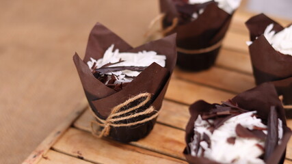 catherine chocolate cake wrapped in brown cake paper and tied with hemp rope, arranged on a hollow wooden baking tray