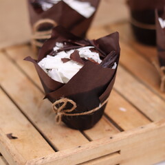 catherine chocolate cake wrapped in brown cake paper and tied with hemp rope, arranged on a hollow wooden baking tray