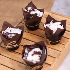 catherine chocolate cake wrapped in brown cake paper and tied with hemp rope, arranged on a hollow wooden baking tray