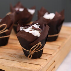 catherine chocolate cake wrapped in brown cake paper and tied with hemp rope, arranged on a hollow wooden baking tray