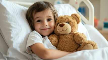 Cute child hugging teddy bear in hospital bed
