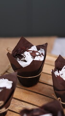 catherine chocolate cake wrapped in brown cake paper and tied with hemp rope, arranged on a hollow wooden baking tray