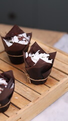 catherine chocolate cake wrapped in brown cake paper and tied with hemp rope, arranged on a hollow wooden baking tray