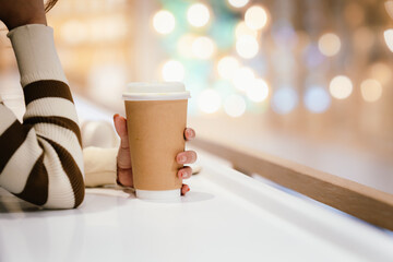 A young woman wearing headphones and glasses, appearing to be an East Asian female, intently uses a white laptop at a cafe table.
