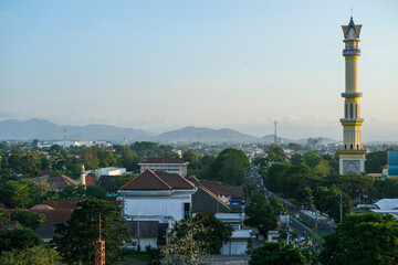 Cityscape view featuring a tall minaret and densely packed rooftops beneath a hazy sky with...