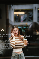A stylish young woman with glasses and braces smiles at the camera, holding a coffee cup in a warmly lit cafe setting.