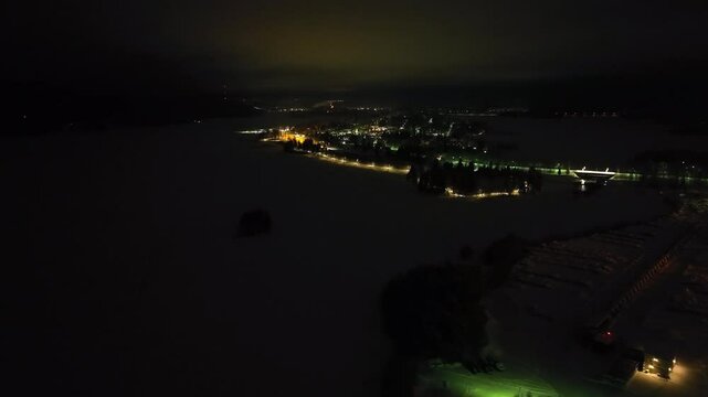 Establishing drone shot the illuminated Nurmes village, winter night in Finland