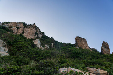 Breathtaking Rocky Cliffs Rising Above Lush Greenery Under a Clear Sky