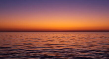 Fototapeta premium Glorious sunset paints the sky orange and red over the sea, with the sun's reflection dancing on the water as gentle waves lap the coast