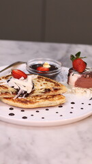 Chewy potato bread is arranged on a white plate and topped with cheese, strawberries and melted...
