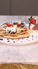 Chewy potato bread is arranged on a white plate and topped with cheese, strawberries and melted chocolate.