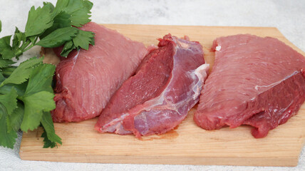 Fresh raw meat at wooden cutting board isolated on grey