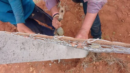 One holds tool while other secures fencing line