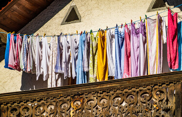 Colorful clothes drying on a line amidst lush green grass in a rural area during bright daytime