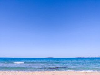 Beach, sea, empty sky and island in the distance