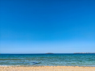 Beach, sea, empty sky and island in the distance
