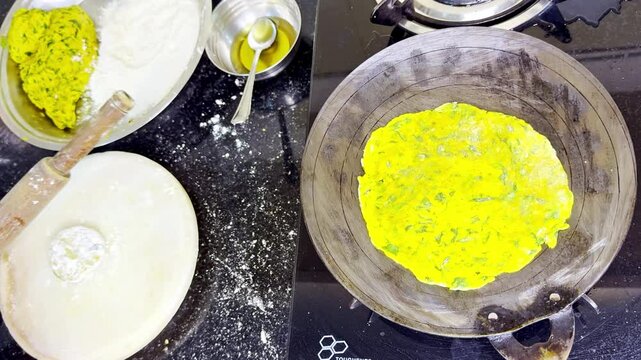 Cook flattens dough using rolling pin on a white slab