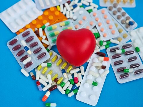 Health and wellness concept with colorful pills scattered around a red heart symbol