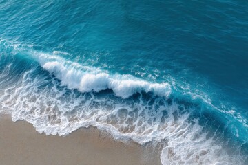 A wave crashes on a sandy beach creating white foam and blue water