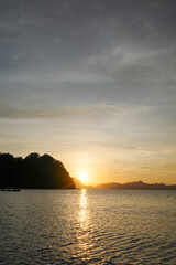 Naklejka premium A beautiful sunset over mountains in Vanilla beach, Coron, Palawan. The last sun ray of the day is the magical moment when the ocean feels warmer. Top tourist attraction in Philippines, Asia