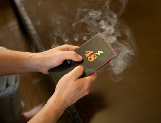 Smartphone with battery indicator showing 48 percent while smoke rises from the device at home during the day