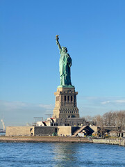 Fototapeta premium The Statue of Liberty, a symbol of New York. The goddess statue is looking left.Vertical. There is construction going on under the pedestal. From the ferry to Liberty Island.