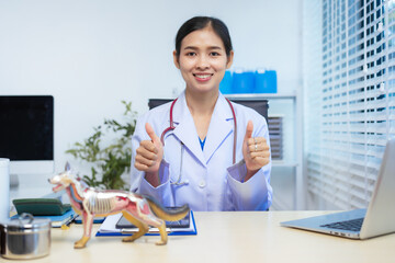 A confident Asian female veterinarian sits at her desk, providing online consultations. She uses...