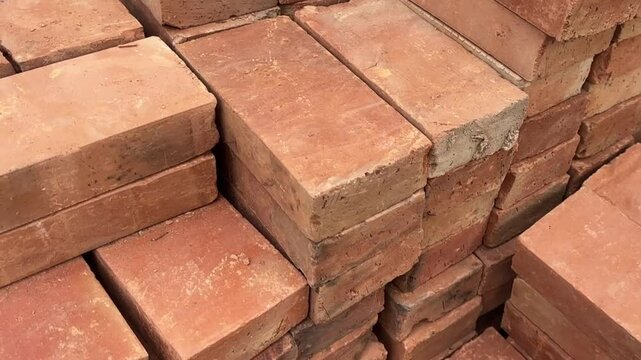Stack of orange bricks arranged in rows with rough texture and construction detail.

