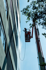 Worker Labour Spray High Pressure Water Cleaning Crane or Construction Gondola at the Building Site