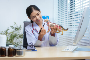 A confident Asian female veterinarian sits at her desk, providing online consultations. She uses...