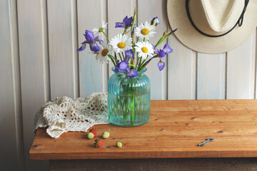 Wildflowers in blue vase decorating wooden table in cozy summer cottage